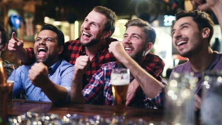 Four guys cheering at a bar
