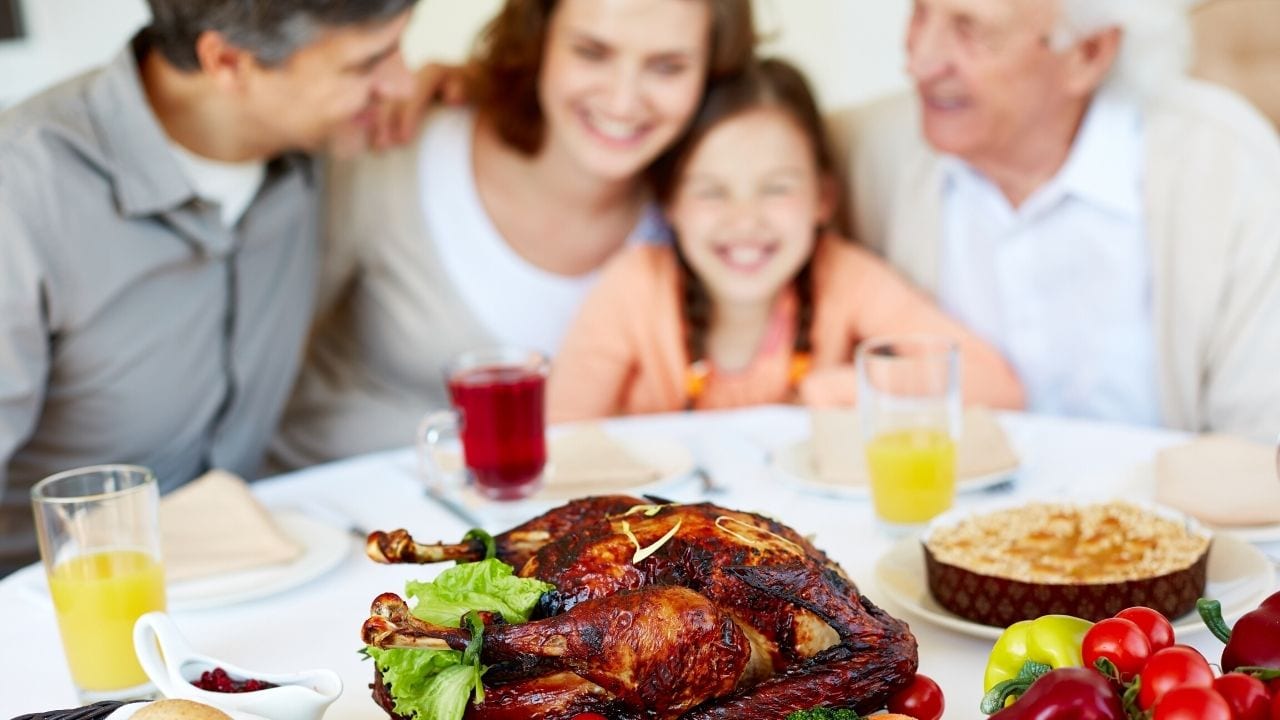 Family sitting at table around Thanksgiving dinner